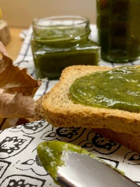 crema al pistacchio su fetta biscottata e barattoli di crema al pistacchio nello sfondo