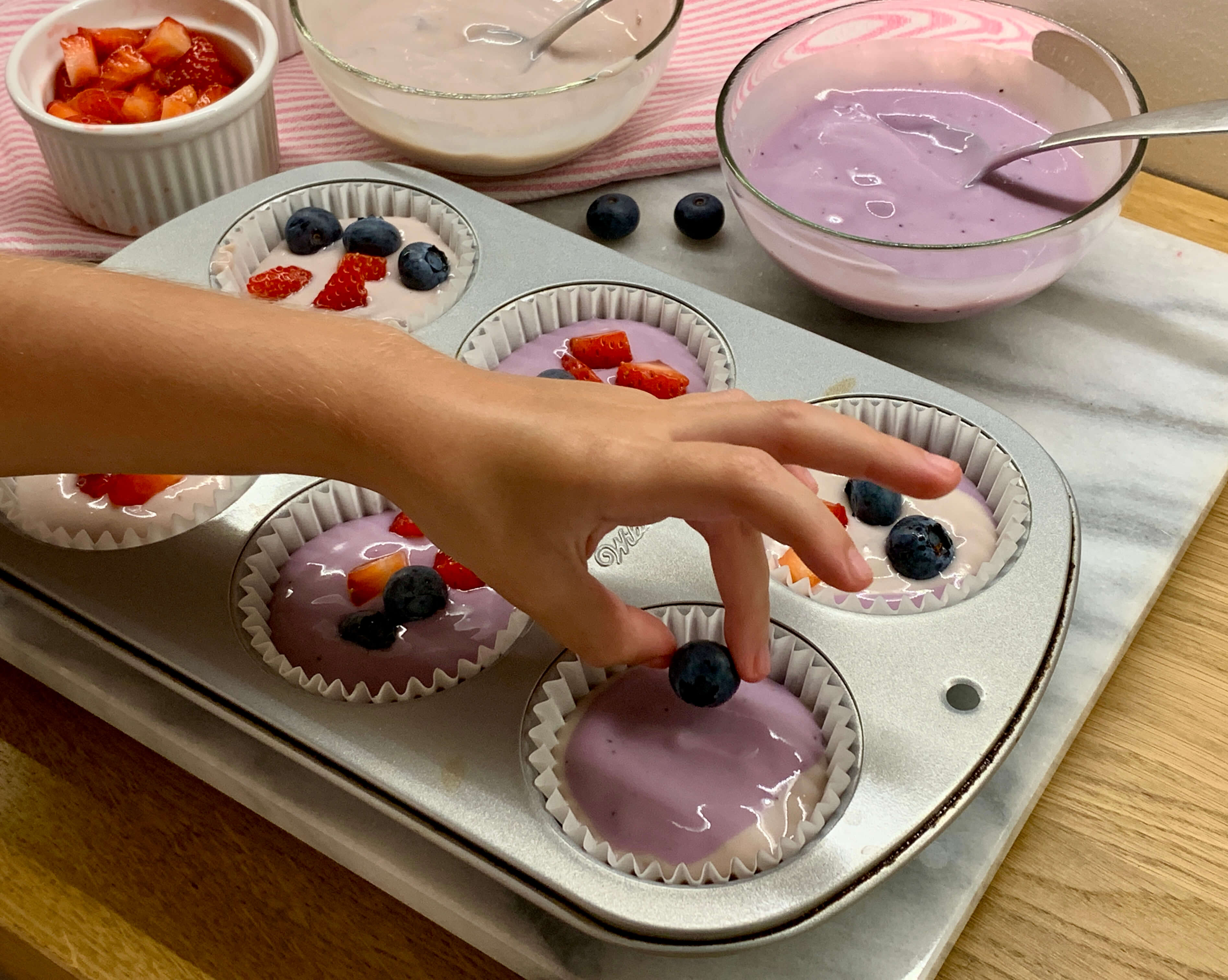 mani di bimba che decorano cupcakes con frutta fresca