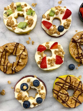 girelle di fette di mela decorate con burro di arachidi, formaggio cremoso, frutta fresca, noci e cioccolato