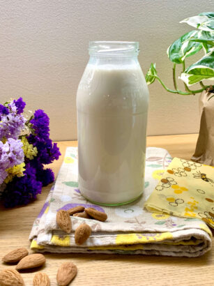 bottiglia di latte con mandorle, fiori e piante attorno